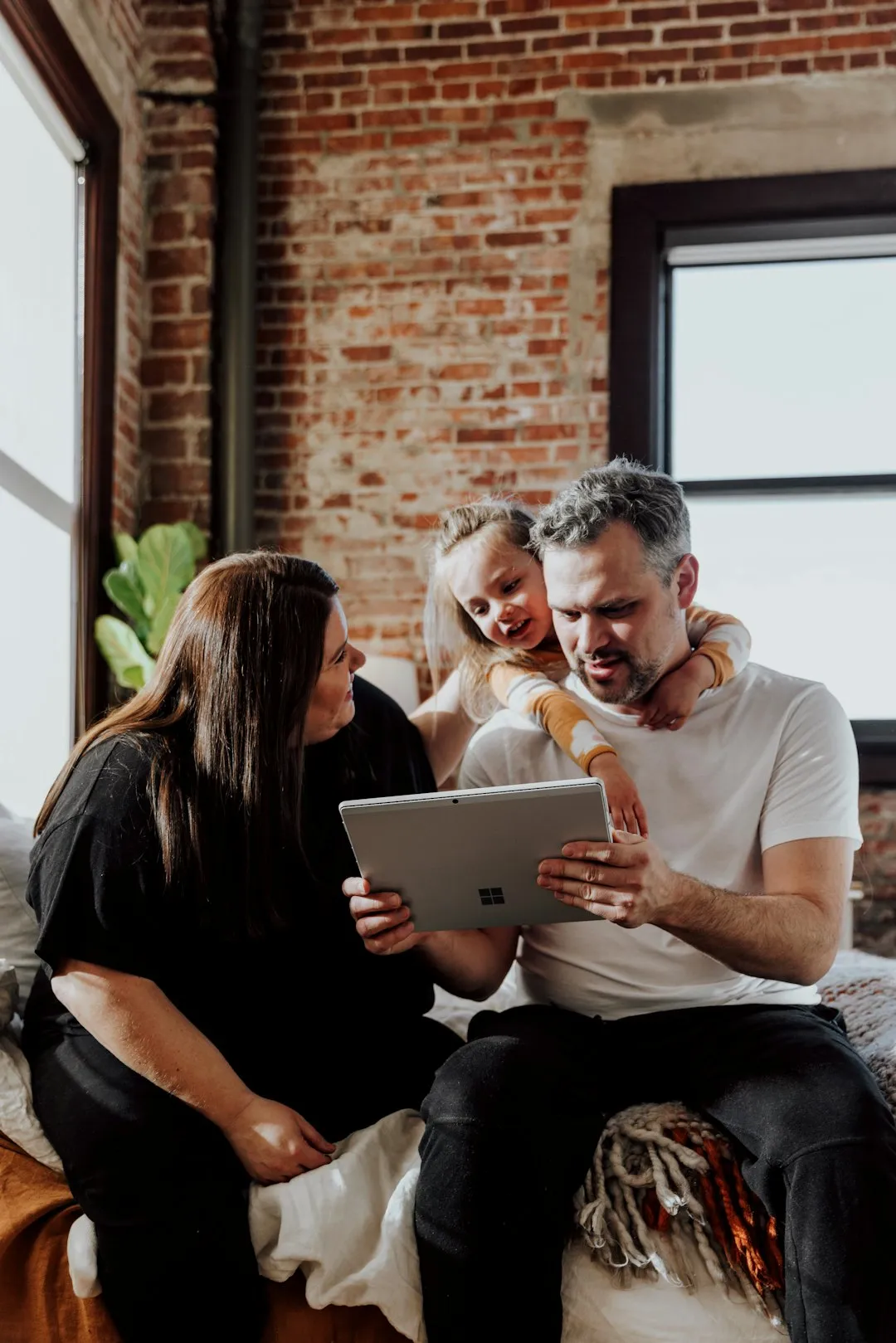 define media marketing a man and two women sitting on a bed looking at a tablet